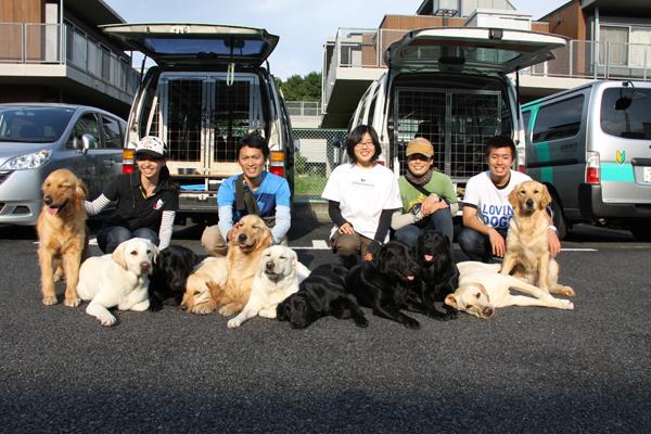 訓練センターに戻り、笑顔で集合写真におさまった6人の訓練士と11頭の訓練犬