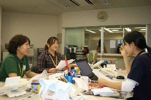 事務所で打合せをする3人の女性職員